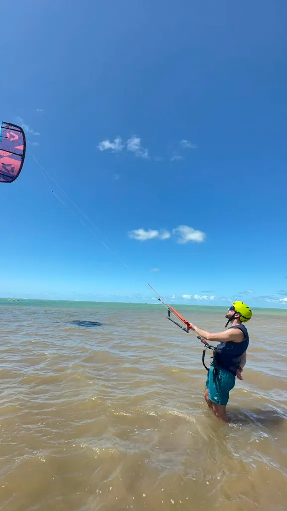 Aluno praticando controle do kite em água rasa