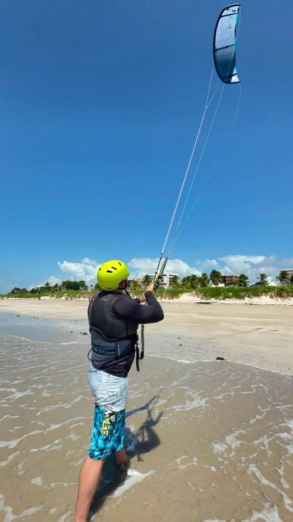 Aluno controlando o kite na beira da praia